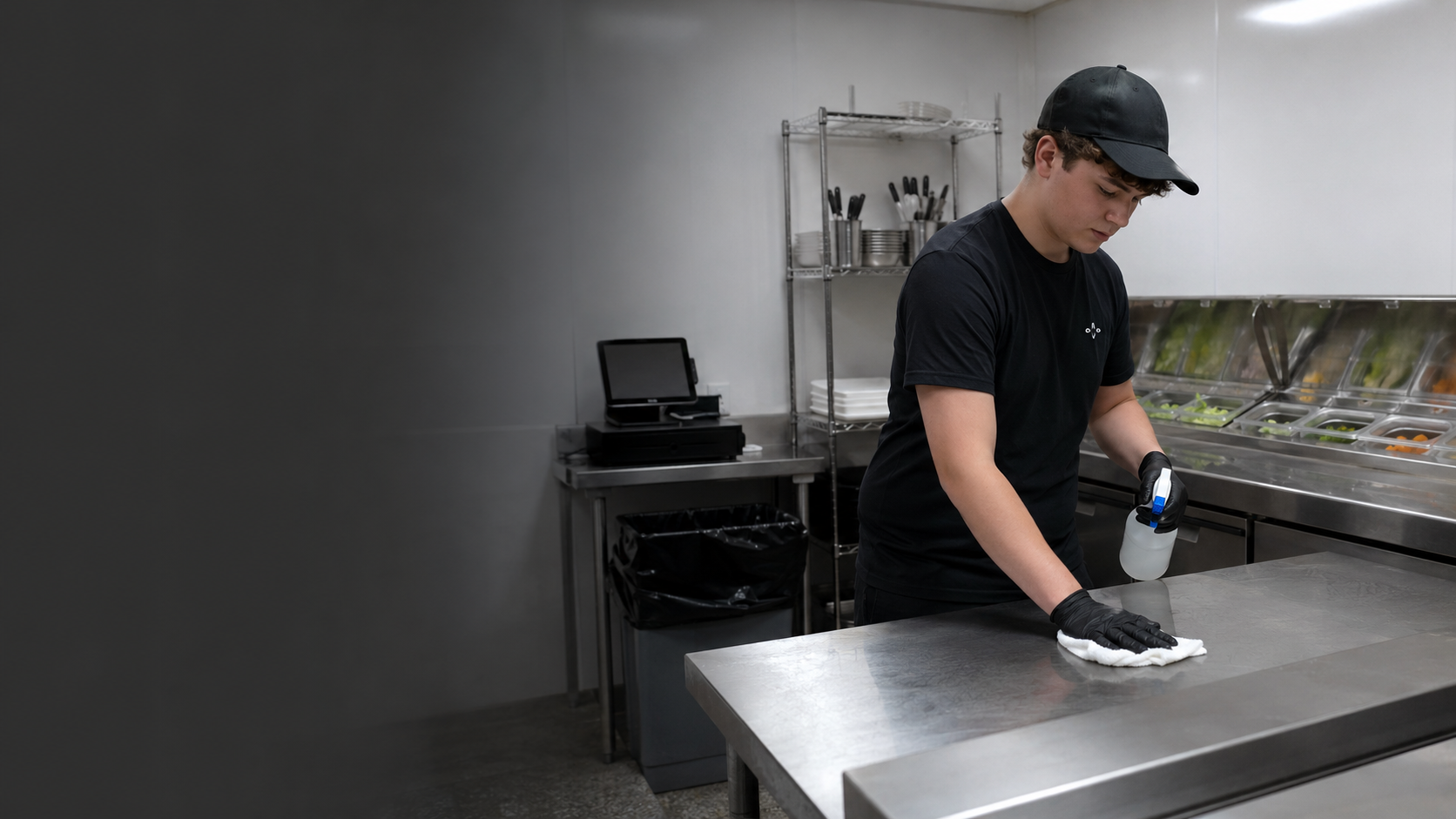 Teenage Krave employee cleaning and sanitizing a food-preparation station after changing tasks