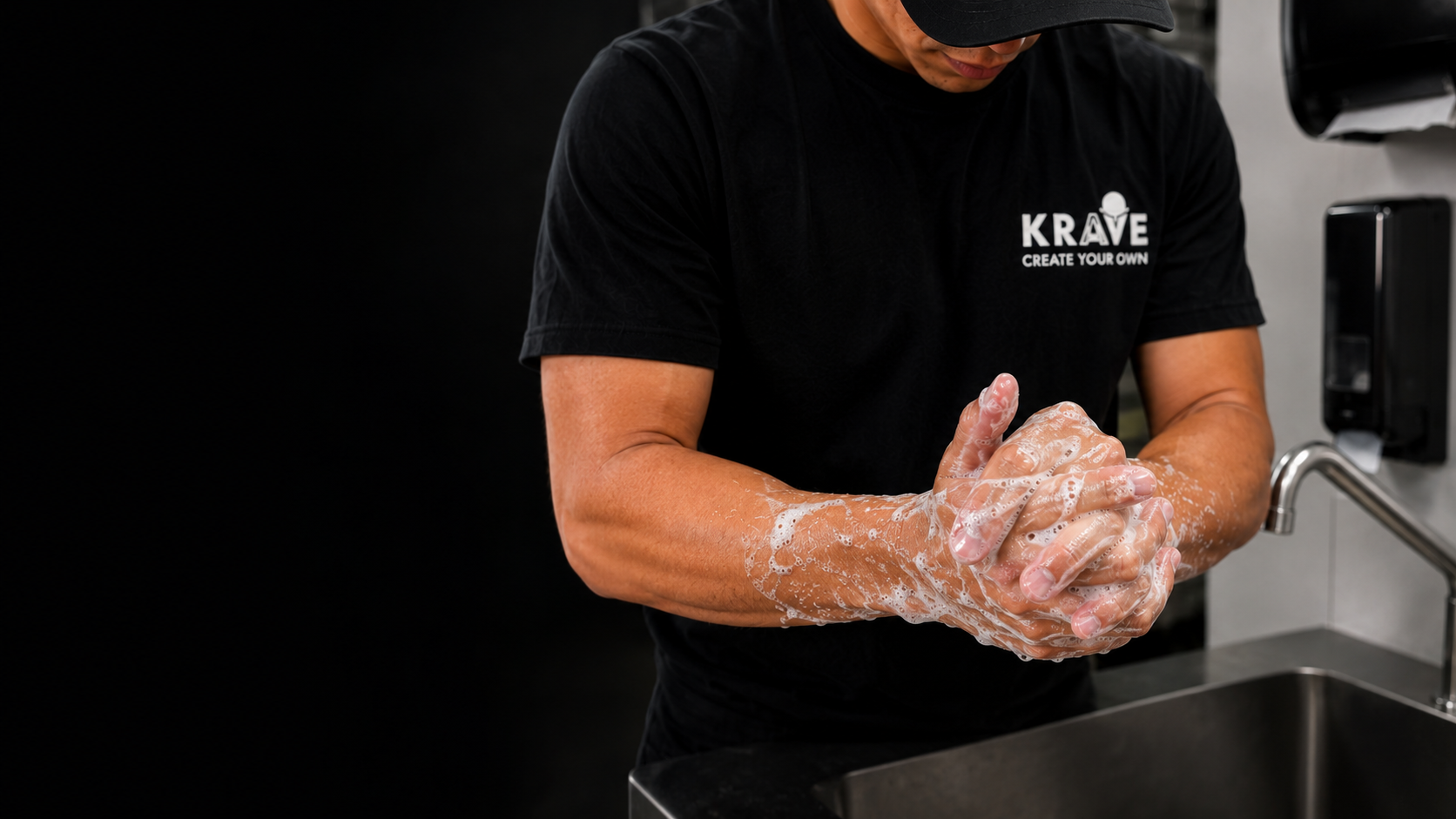 A Krave employee scrubbing lathered hands with the water turned off